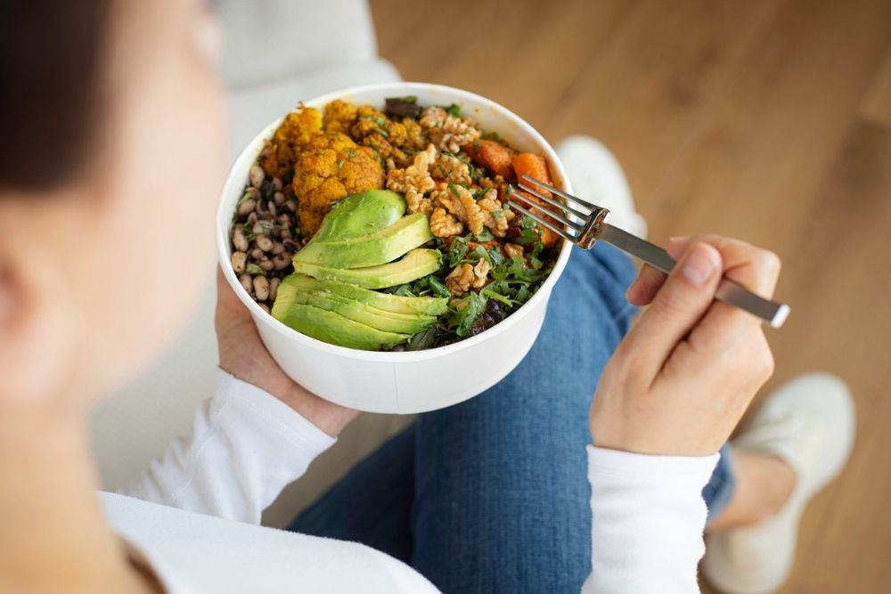 Person holding a colorful bowl of healthy food, symbolizing nutritious choices in recovery.