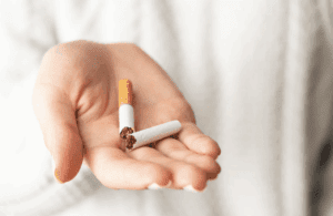 A hand holding a broken cigarette.